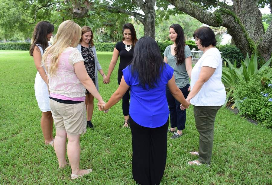 Women holding hands in circle outside